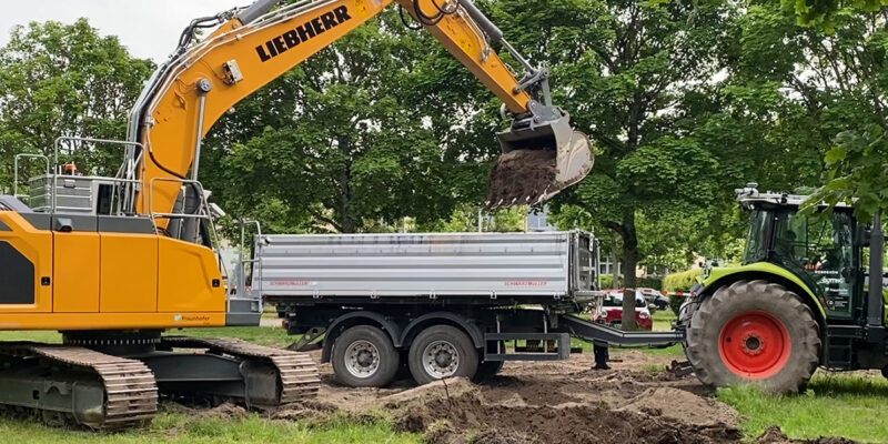 Autonomer Bagger belädt nach selbstständig durchgeführtem Aushubvorgang ein autonom herbeigefahrenes Transportfahrzeug (Traktor mit Anhänger) mit Erdaushub. (Autonome Systeme des Fraunhofer IOSB) (Foto: ROBDEKON / Fraunhofer-Institut für Optronik, Systemtechnik und Bildauswertung IOSB)