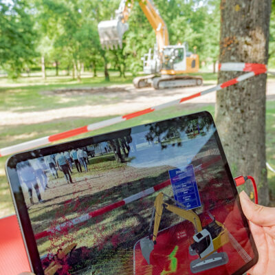 Bagger (Hintergrund) mit digitalem Zwilling auf einem Tablet für
Augmented-Reality durch Technologie des KIT-ISAS. Eingeblendet werden Sensordaten des Baggers als gefärbte Punktwolke. Es besteht auch die Möglichkeit zur Fernsteuerung des Baggers durch das Tablet. (Foto: ROBDEKON / Fraunhofer-Institut für Optronik, Systemtechnik und Bildauswertung IOSB) (Foto: ROBDEKON / Fraunhofer-Institut für Optronik, Systemtechnik und Bildauswertung IOSB)