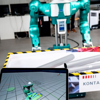 Humanoider Greifroboter des KIT-H2T (Hintergrund) greift kontaminierte Teile autonom aus einer Kiste um sie für die Reinigung vorzubereiten. Auf dem Tablet (Vordergrund) ist der digitaler Zwilling mit der Anzeige des vom Roboter gewählten Griffs zu sehen. Per Tablet kann der Operator bei Bedarf eingreifen. (Foto: ROBDEKON / Fraunhofer-Institut für Optronik, Systemtechnik und Bildauswertung IOSB) (Foto: ROBDEKON / Fraunhofer-Institut für Optronik, Systemtechnik und Bildauswertung IOSB)