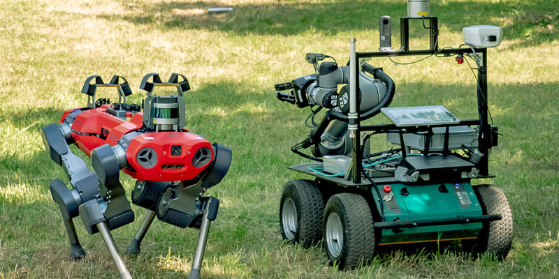Laufroboter (links) als Scout für die Suche nach Gefahrstoffen. Die gefundene Position des Gefahrstoffs wird an die mobile Plattform (rechts) zur Aufnahme mit dem Greifarm übermittelt. (Systeme des Forschungszentrums Informatik Karlsruhe FZI) (Foto: ROBDEKON / Fraunhofer-Institut für Optronik, Systemtechnik und Bildauswertung IOSB)