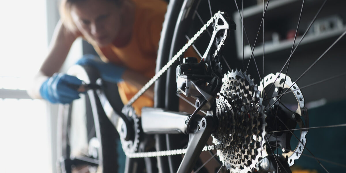Frau repariert mit Gummihandschuhen Fahrrad mit Werkzeugen, Nahaufnahme (Foto: Ivan-balvan (iStock))