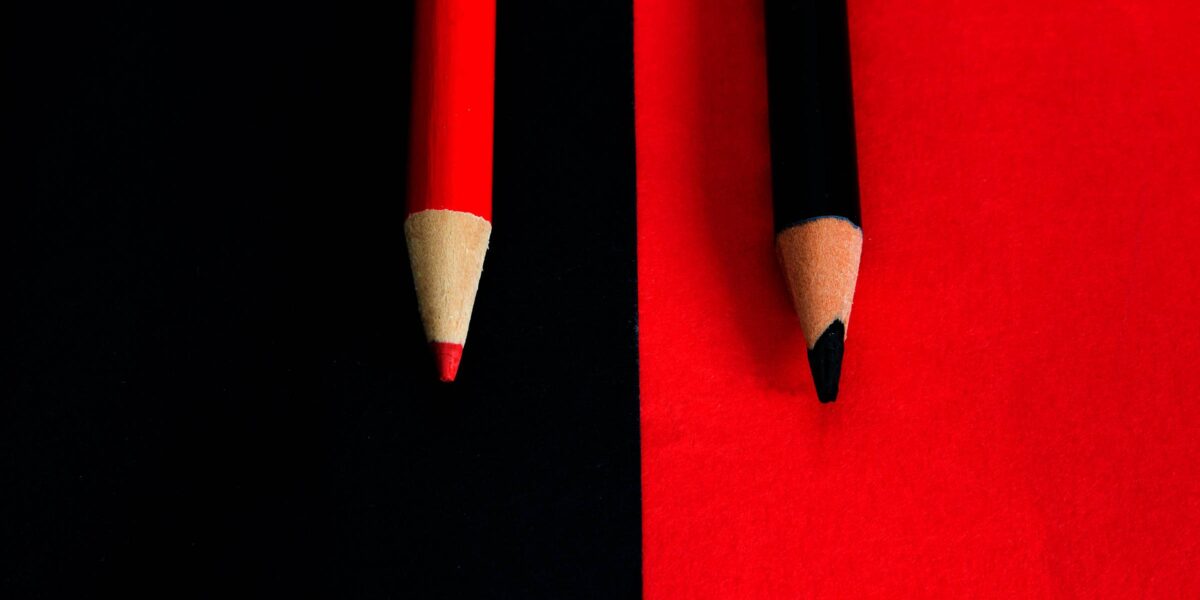 Bleistiftspitzen auf farbigen Hintergründen, roter Stift auf schwarz, schwarzer Stift auf rot (Foto: carlofornitano (iStock))